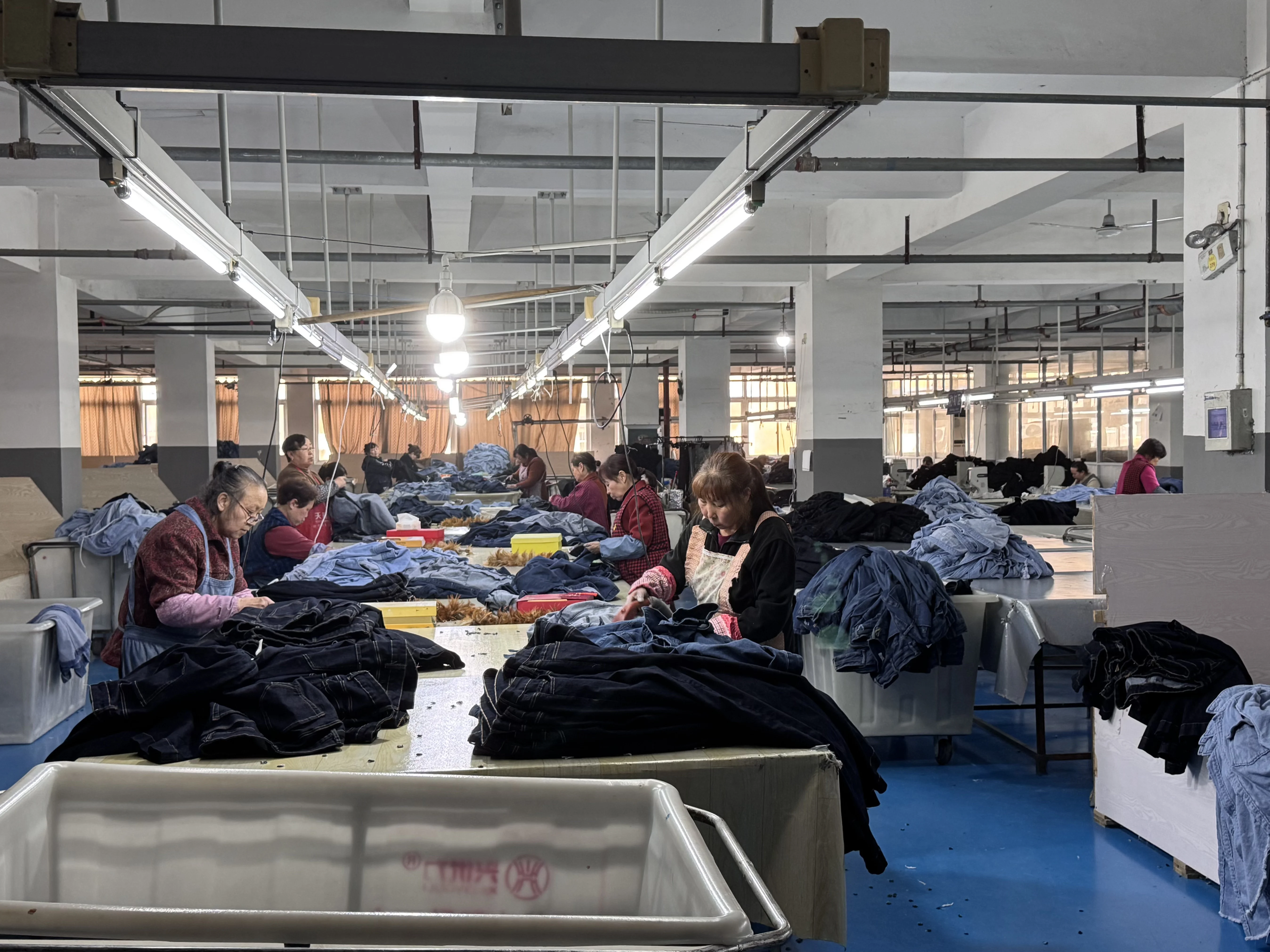 工人在生产车间分拣和整理牛仔服装